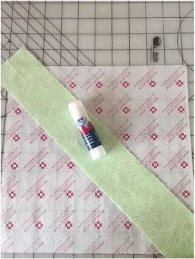 Picture of lapel pen, fabric strip, and foundation papers for quilting.